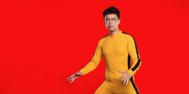 Phil Wang in an orange and black jumpsuit in an action pose